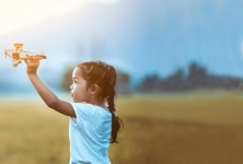 Girl with airplane toy in field