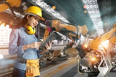 Female engineer in a factory controls an industrial robot.
